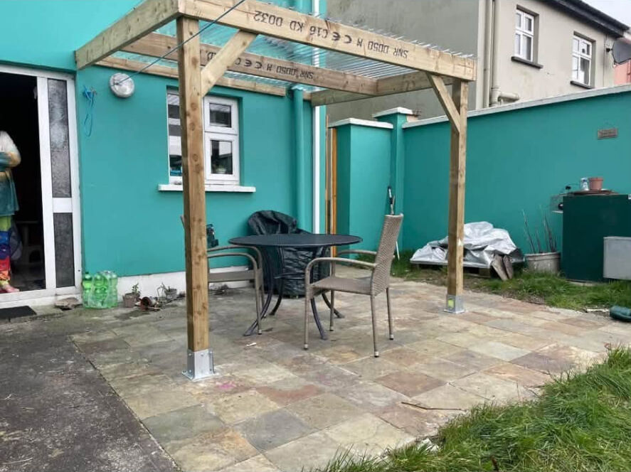Timber pergola with clear roof sheets over a paved patio with table and chairs