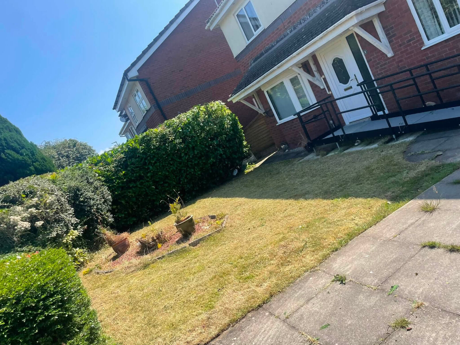 Front lawn cut and hedges trimmed outside a red-brick house