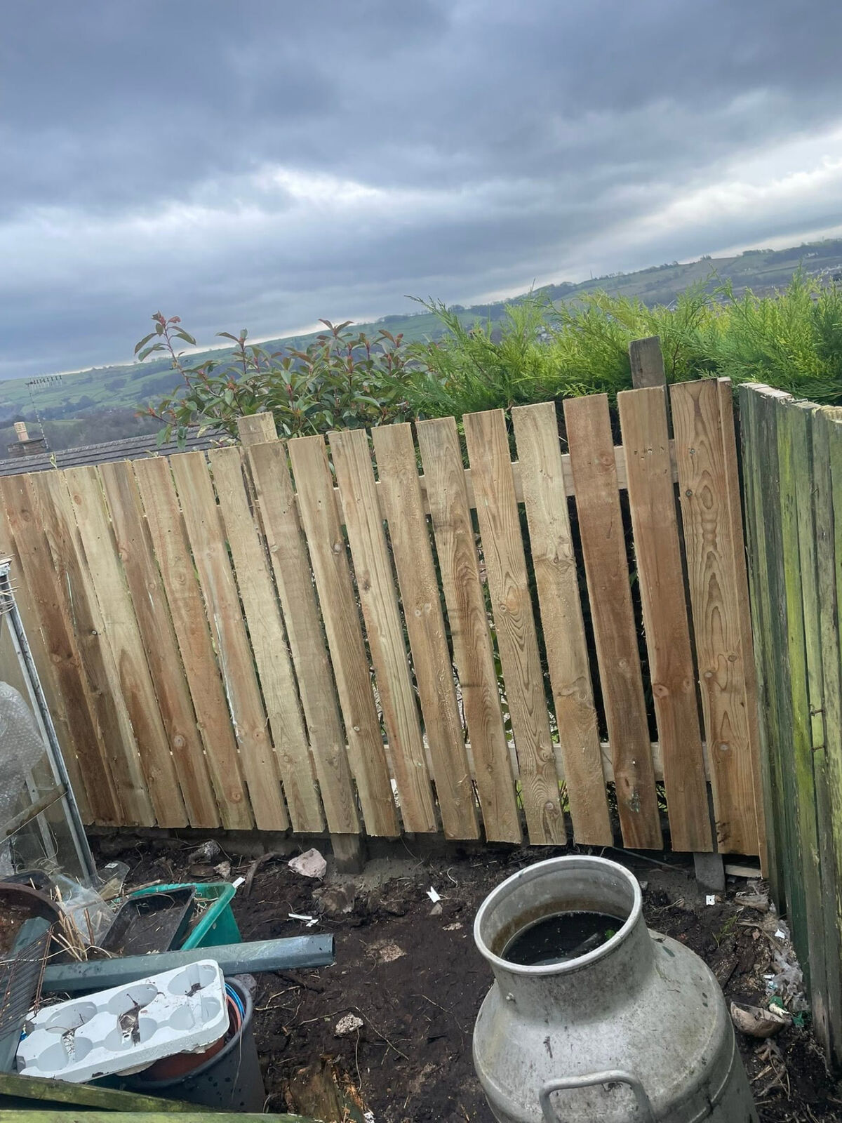 Newly fitted timber boarded garden fence with hills in the background